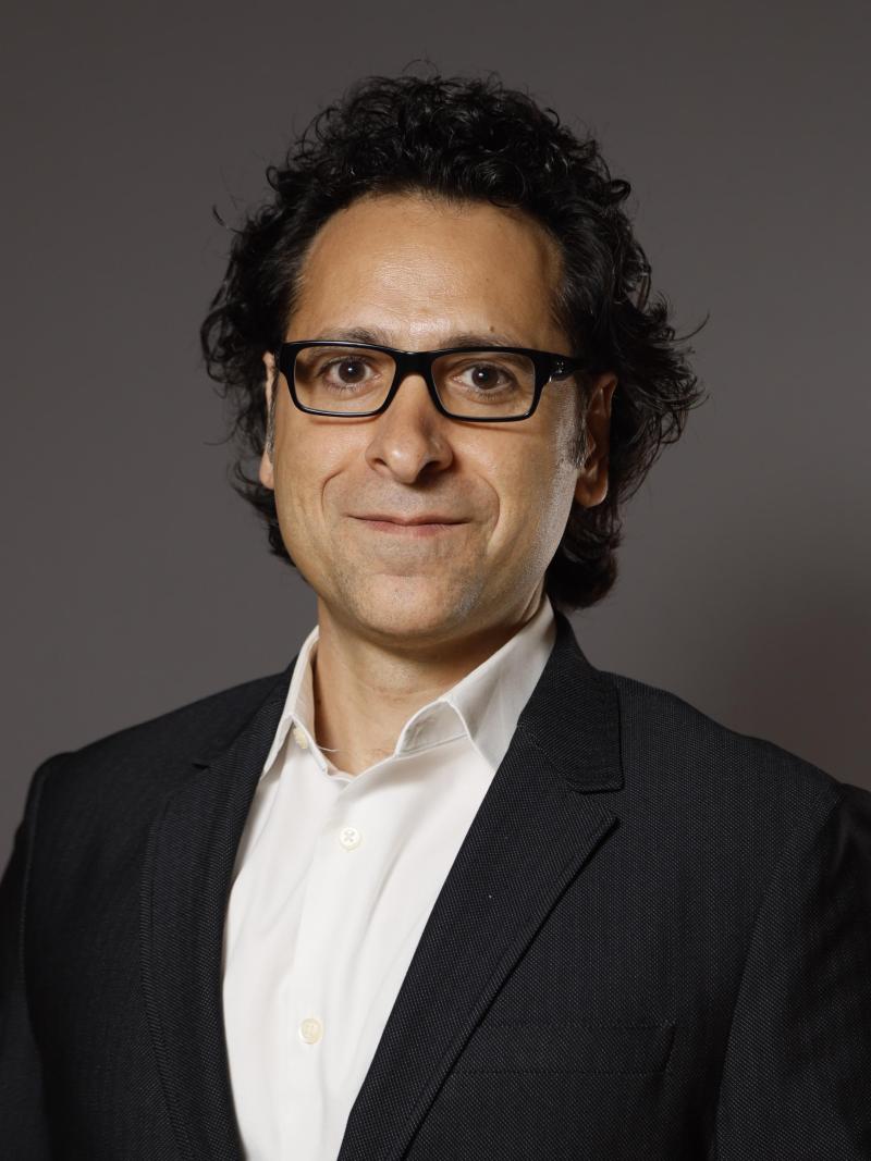 Zak Kassas in a black blazer and button down shirt