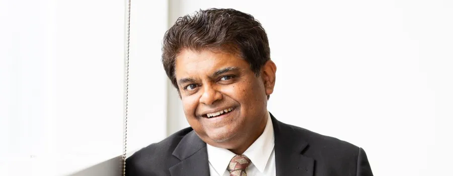 Sanjay Krishna in a tie by a window.