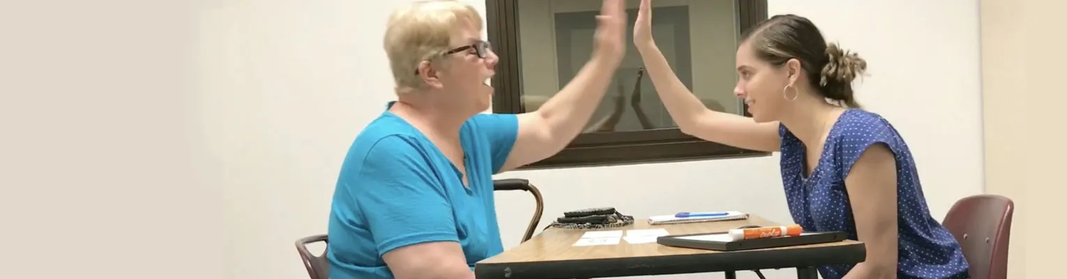 two people about to clap hands from across a table