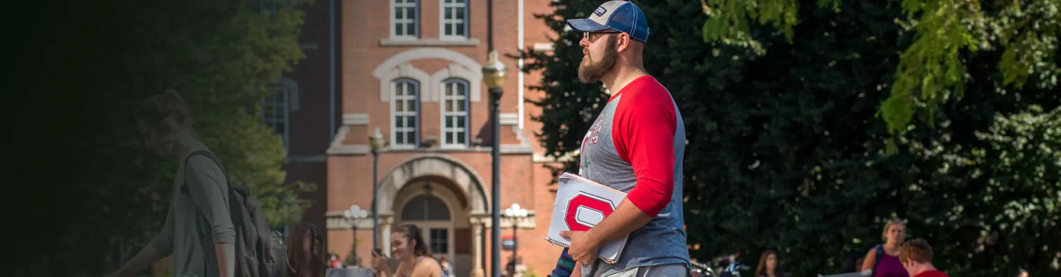 Person walking with Block O folder in front of University Hall