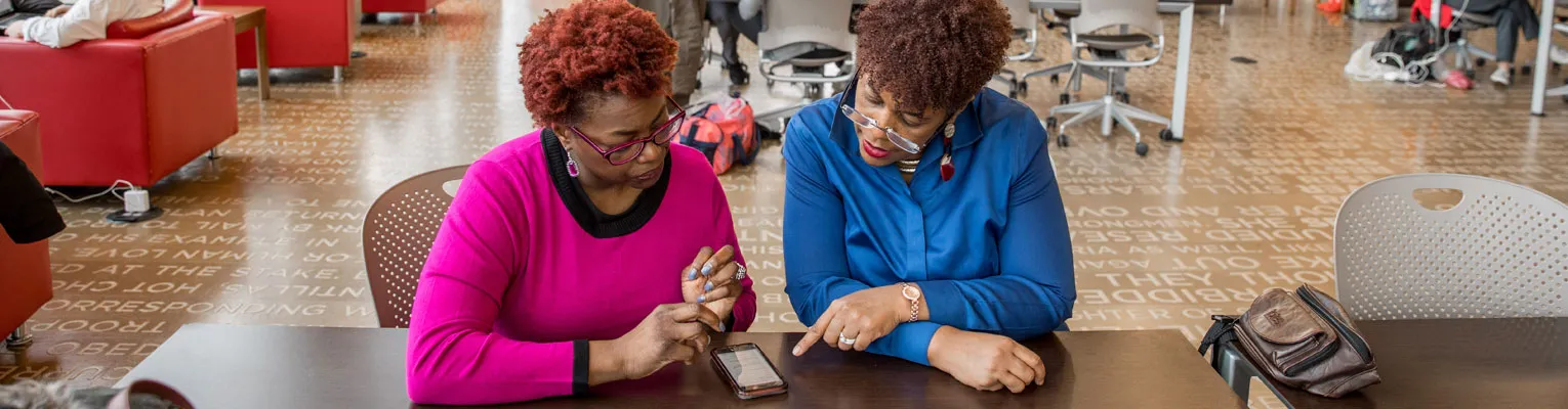 people in library reviewing information on a phone