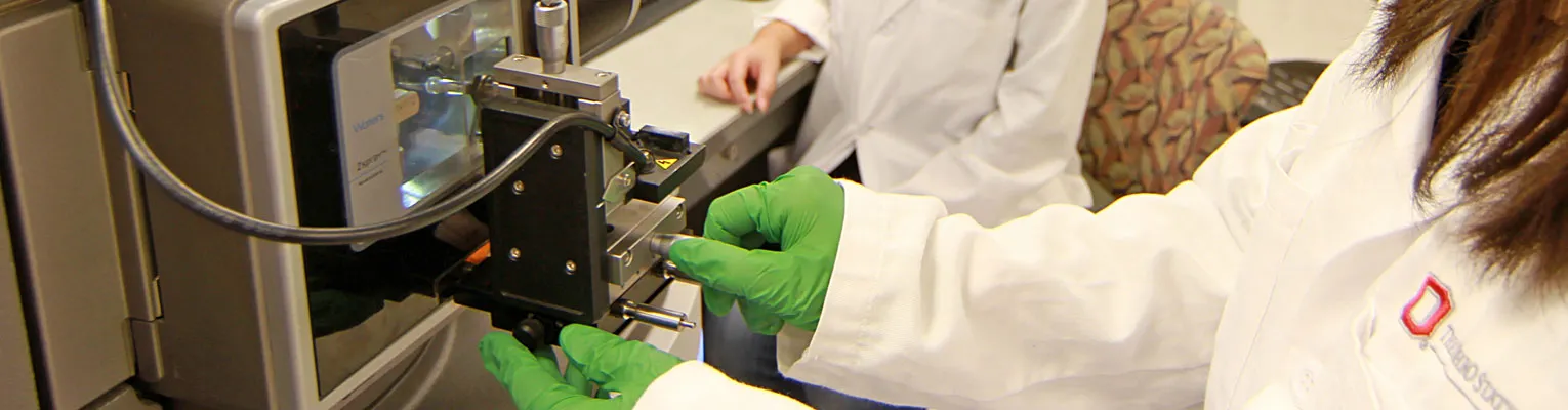 researcher with green gloves using a lab instrument