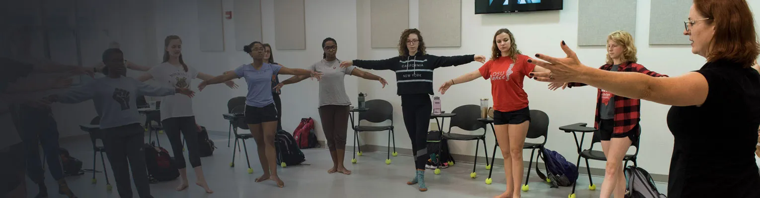 Students and teacher in dance stretching arms out