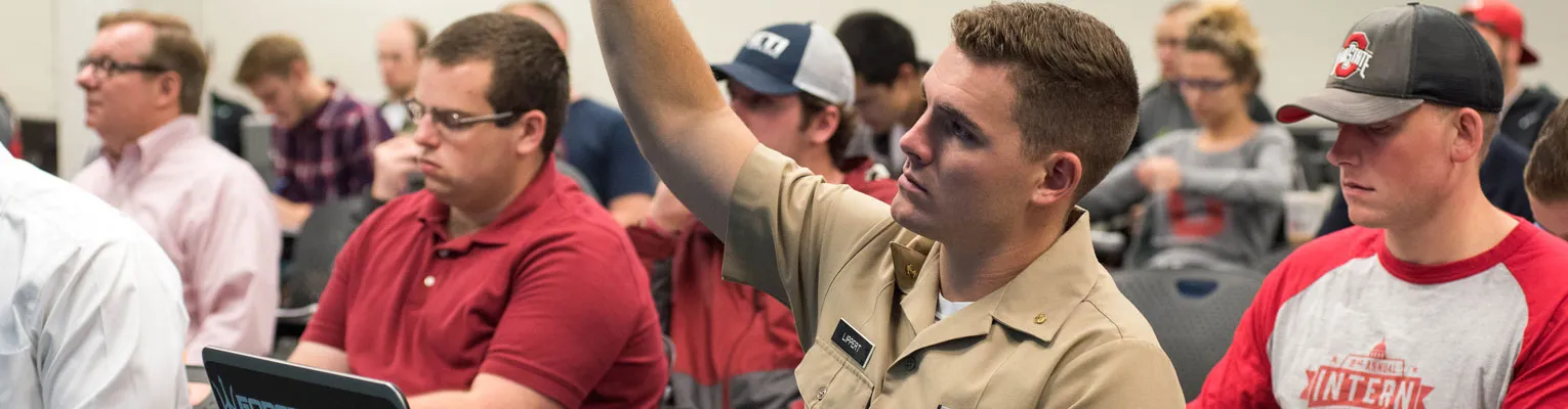 classroom setting with man raising his hand to volunteer