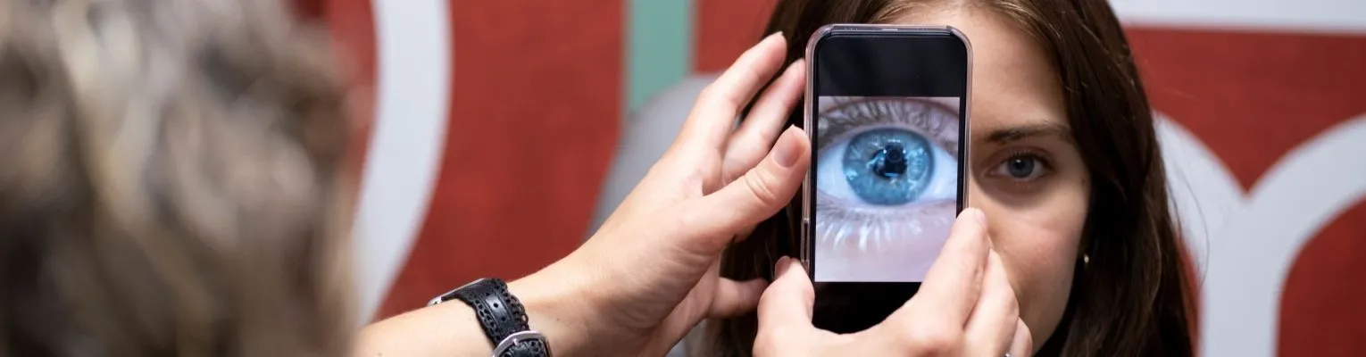 woman using iphone to examine the eye of another woman