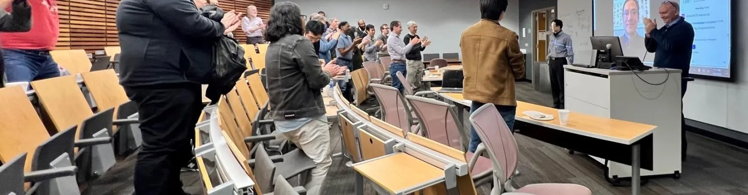 classroom setting with people standing and clapping