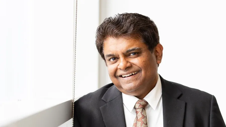 Photo of Sanjay Krishna in a tie by a window.