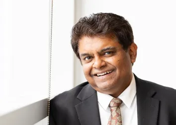 Photo of Sanjay Krishna in a tie by a window.