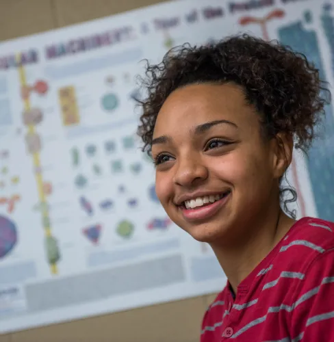 Female Microbiology student standing in front of a research presentation poster