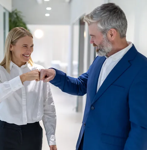 business man and women fist bumping in a workspace hallway