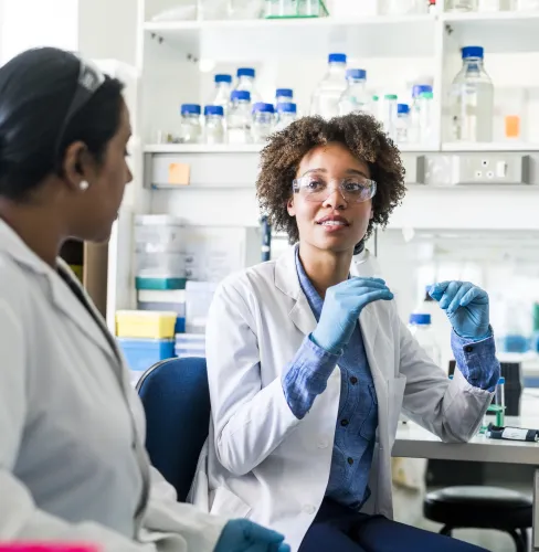 two women in a laboratory speaking to each other while sitting