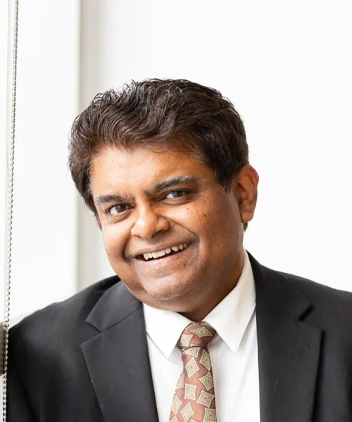 Sanjay Krishna in a tie by a window.