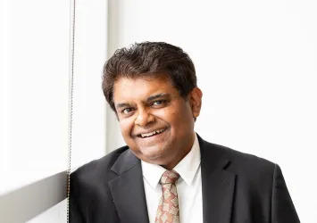 Sanjay Krishna in a tie by a window.